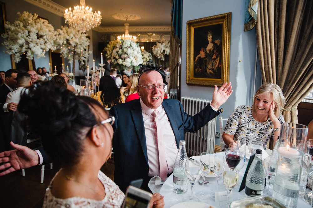 wedding guest wearing hat while singing and laughing with guests