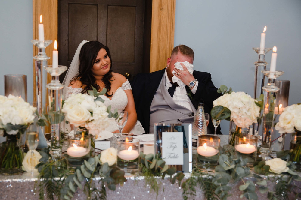 close up photograph of groom holding head in hands during speeches