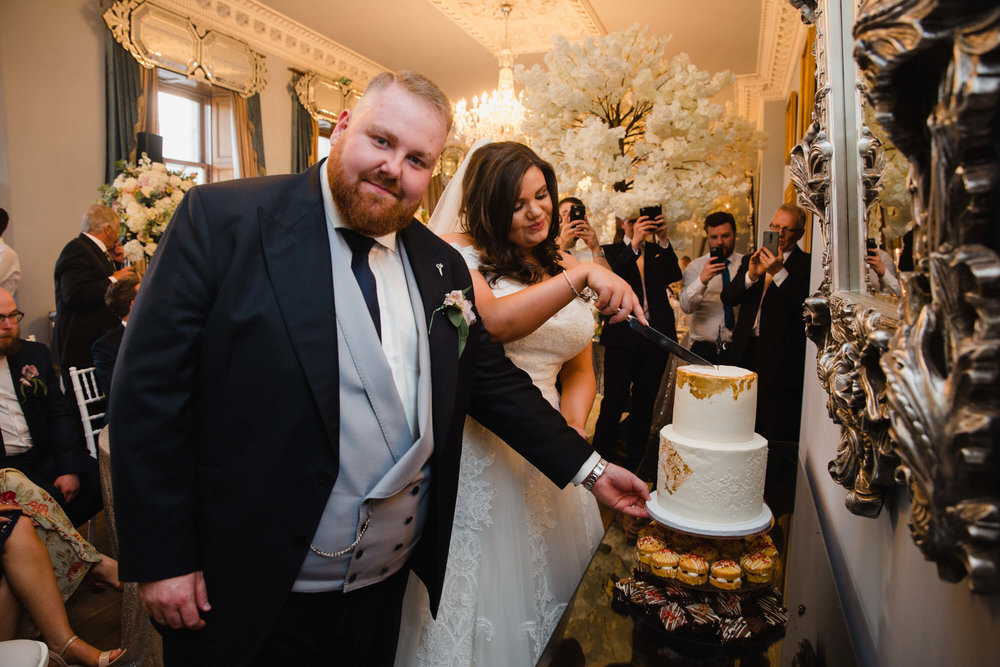 bride and groom cutting wedding cake at haigh hall