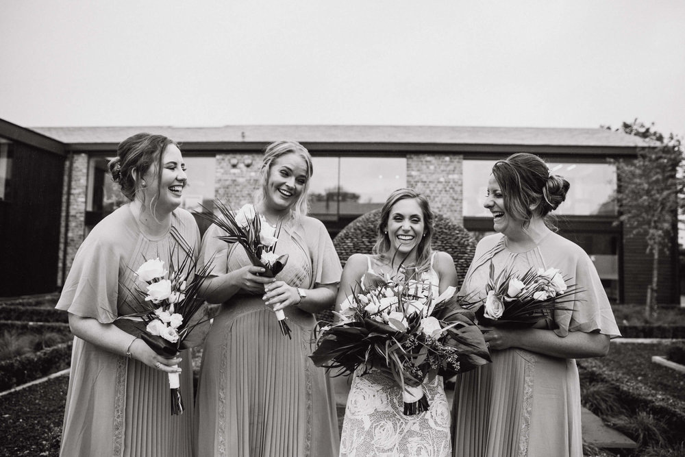 black and white photograph of bride laughing with bridesmaids at colony base