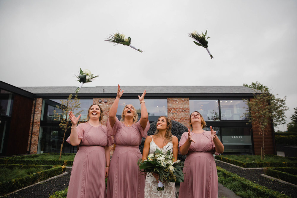 bridesmaids throw wedding bouquets in air 