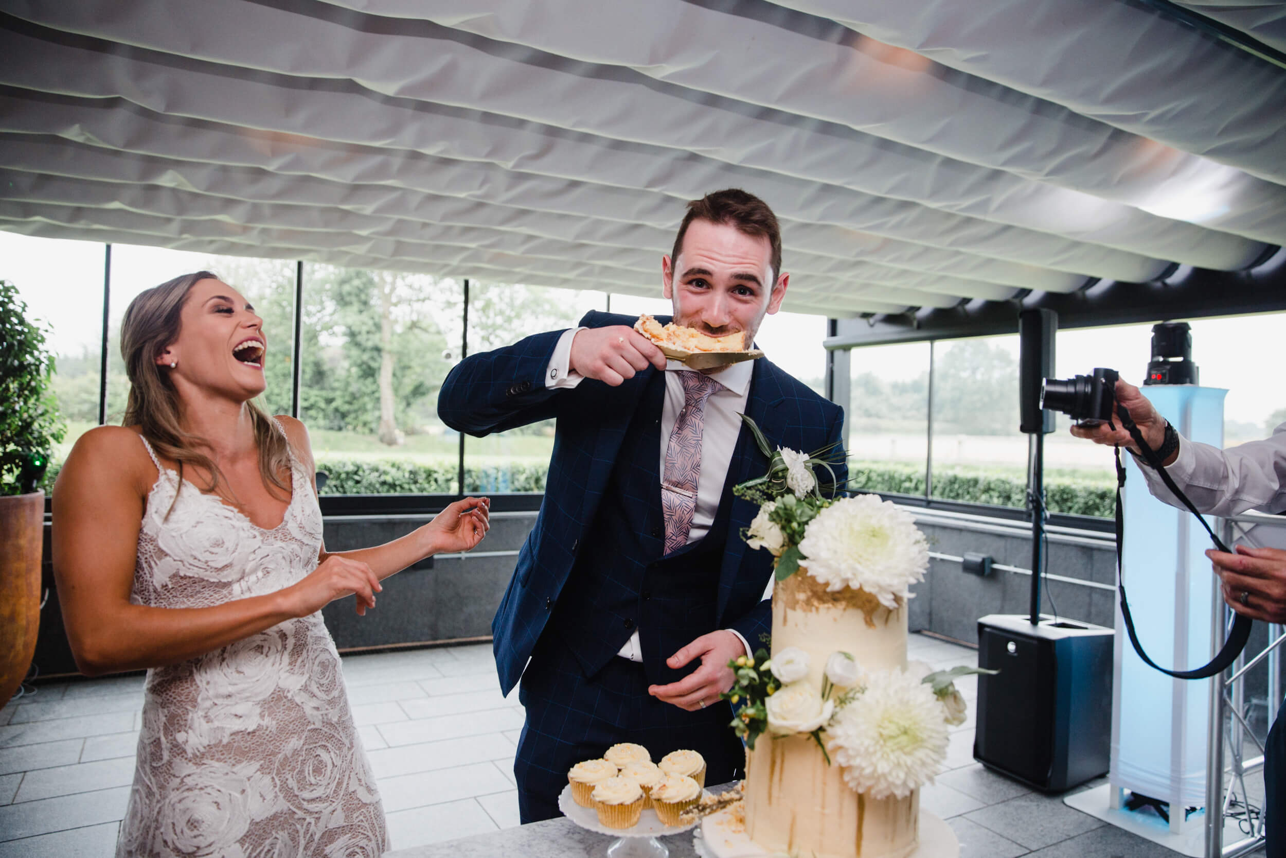 groom eats slice of wedding cake with bride laughing at The Colony HQ