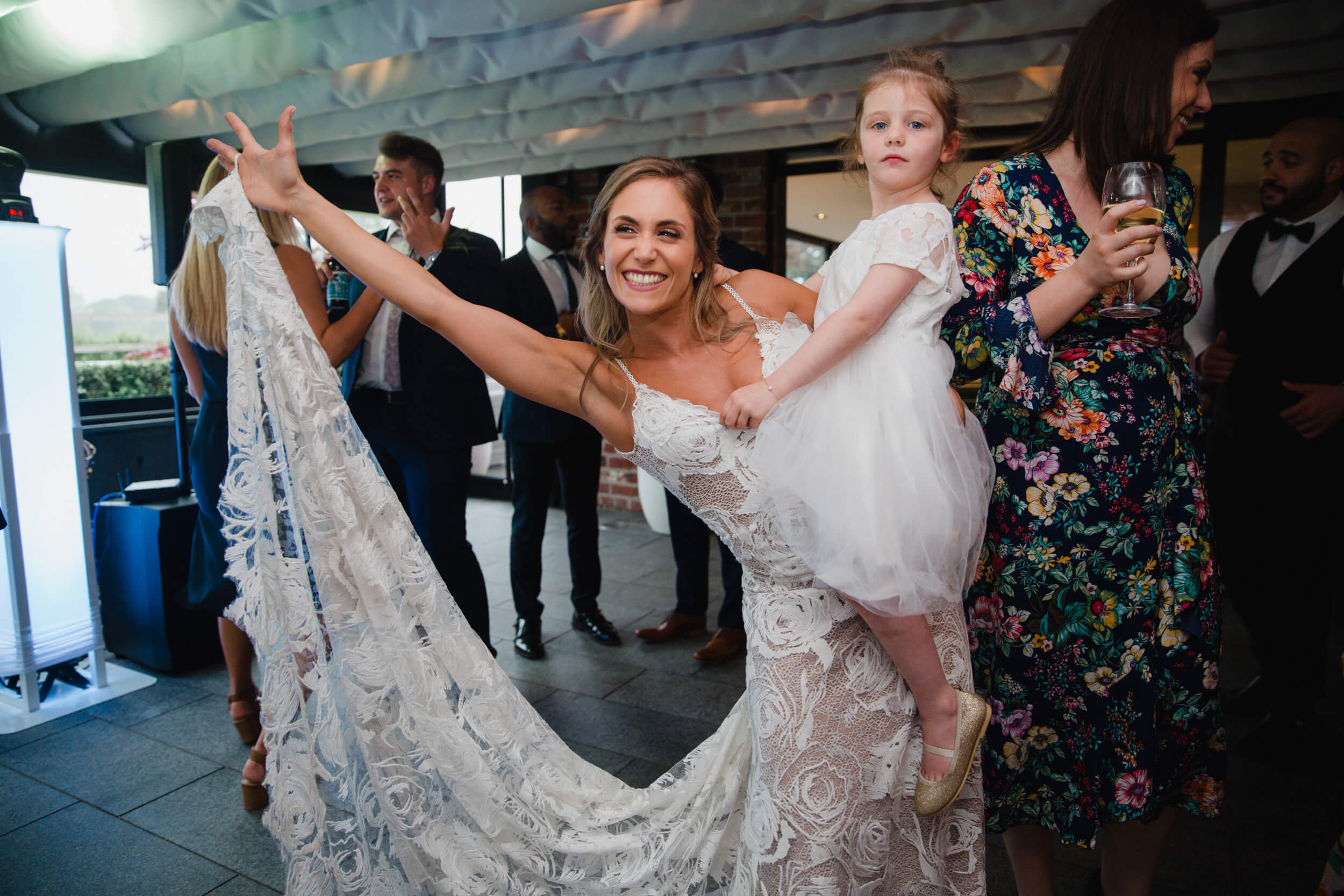bride holding flower girl lifting wedding dress up off the dance floor