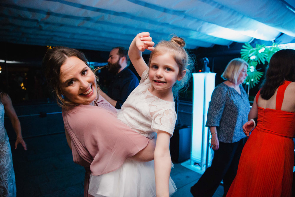 bridesmaid holding flower girl on dance floor of wedding