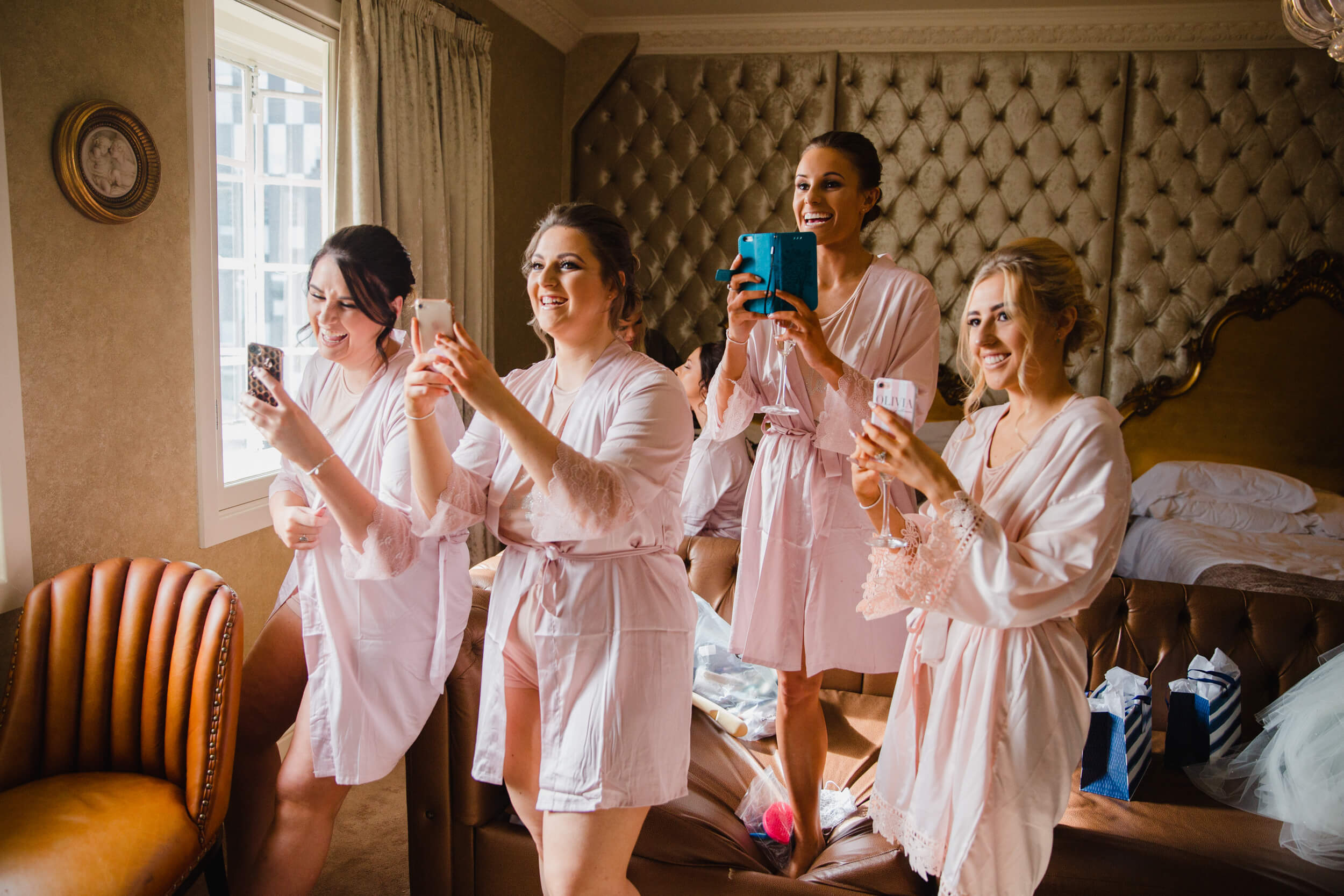 all bridesmaids in hotel suite taking photographs of bride