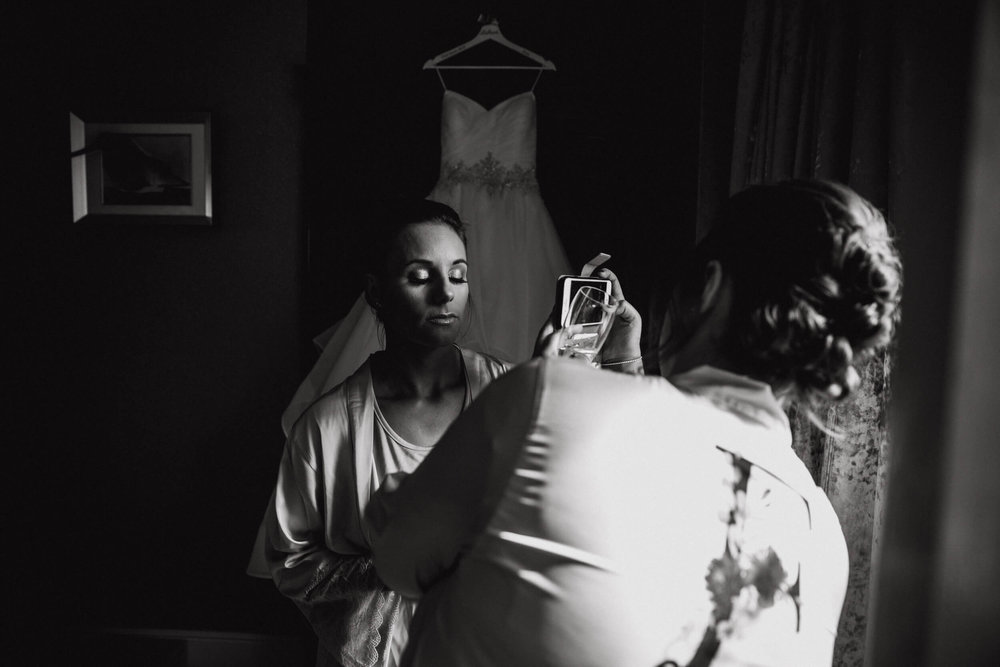 low exposure black and white photograph of bridesmaid having makeup applied