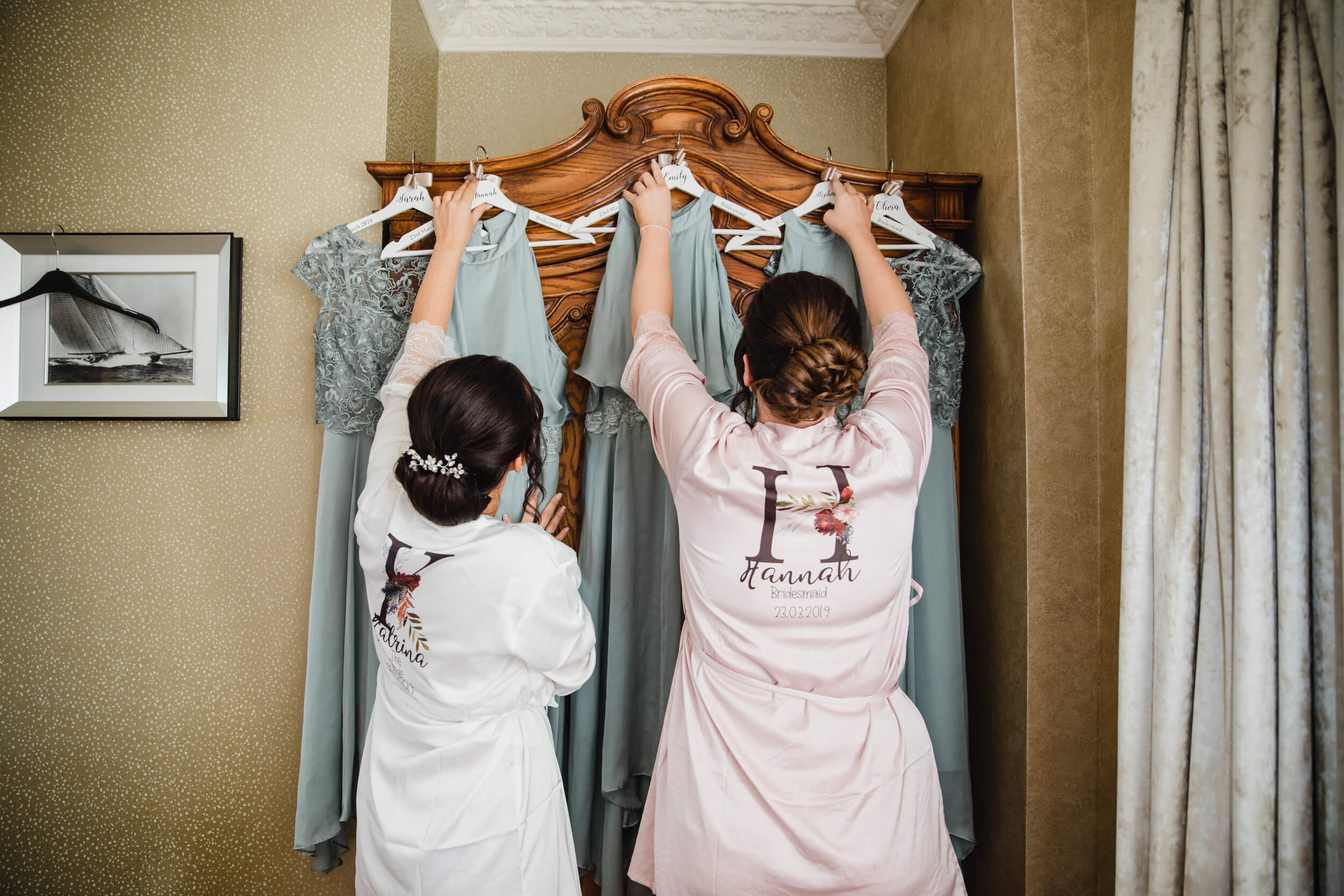 bride and bridesmaid hanging dresses onto wardrobe