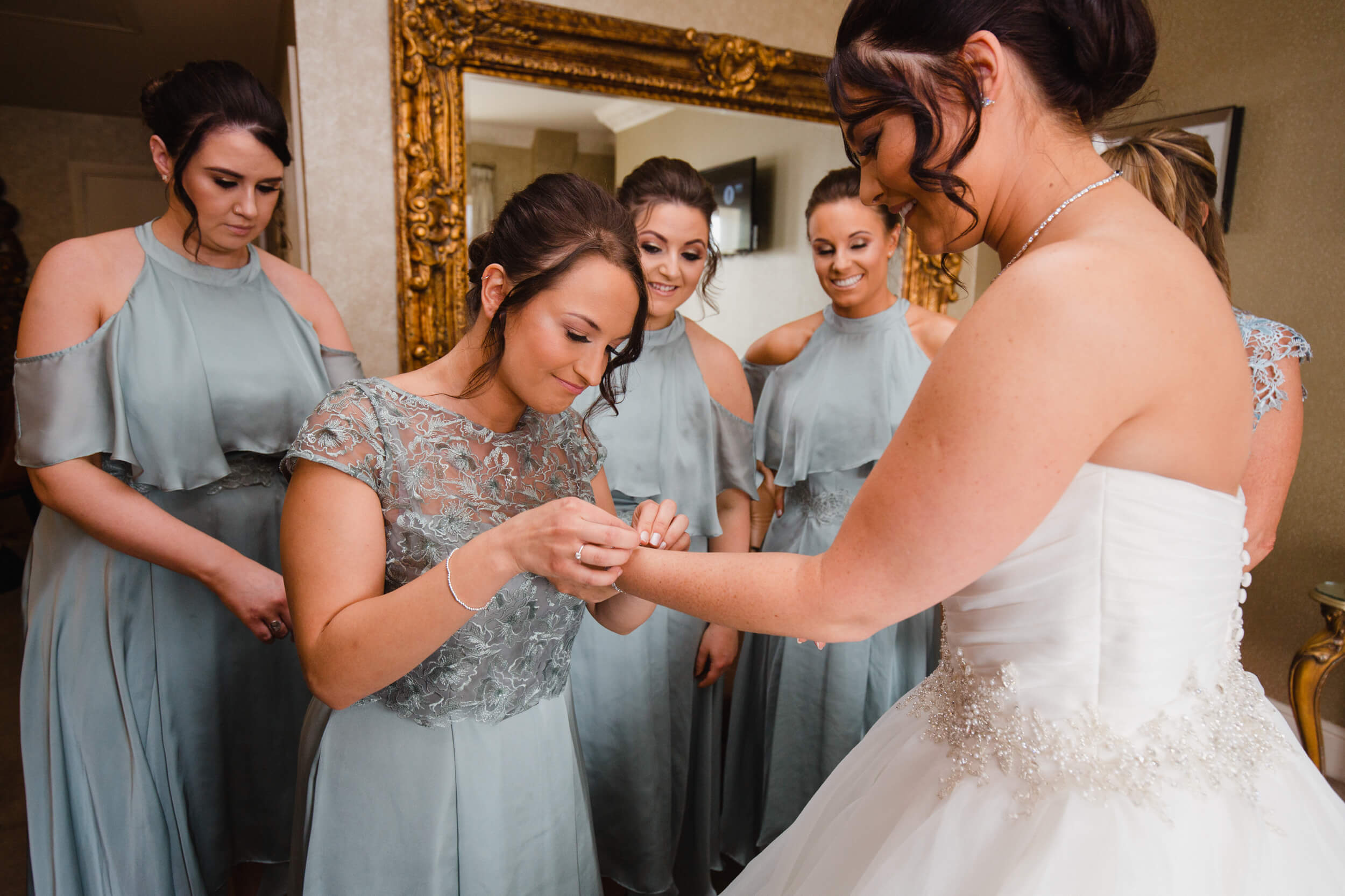 bridesmaid attaches wedding bracelet onto brides wrist