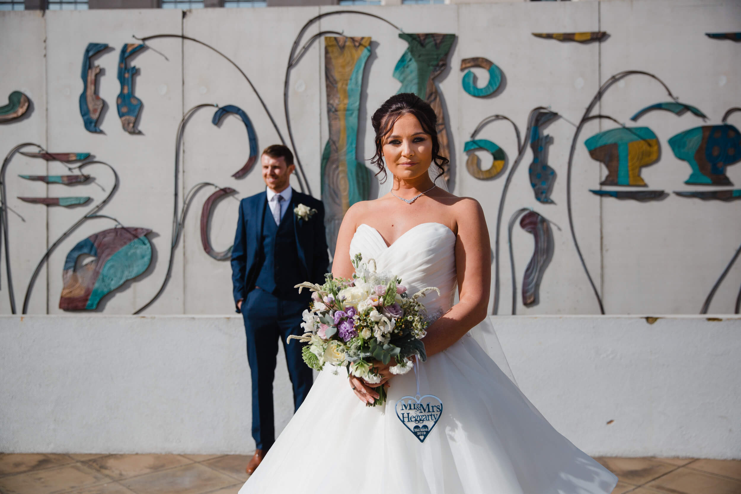 bride in foreground of photograph posing with bouquet