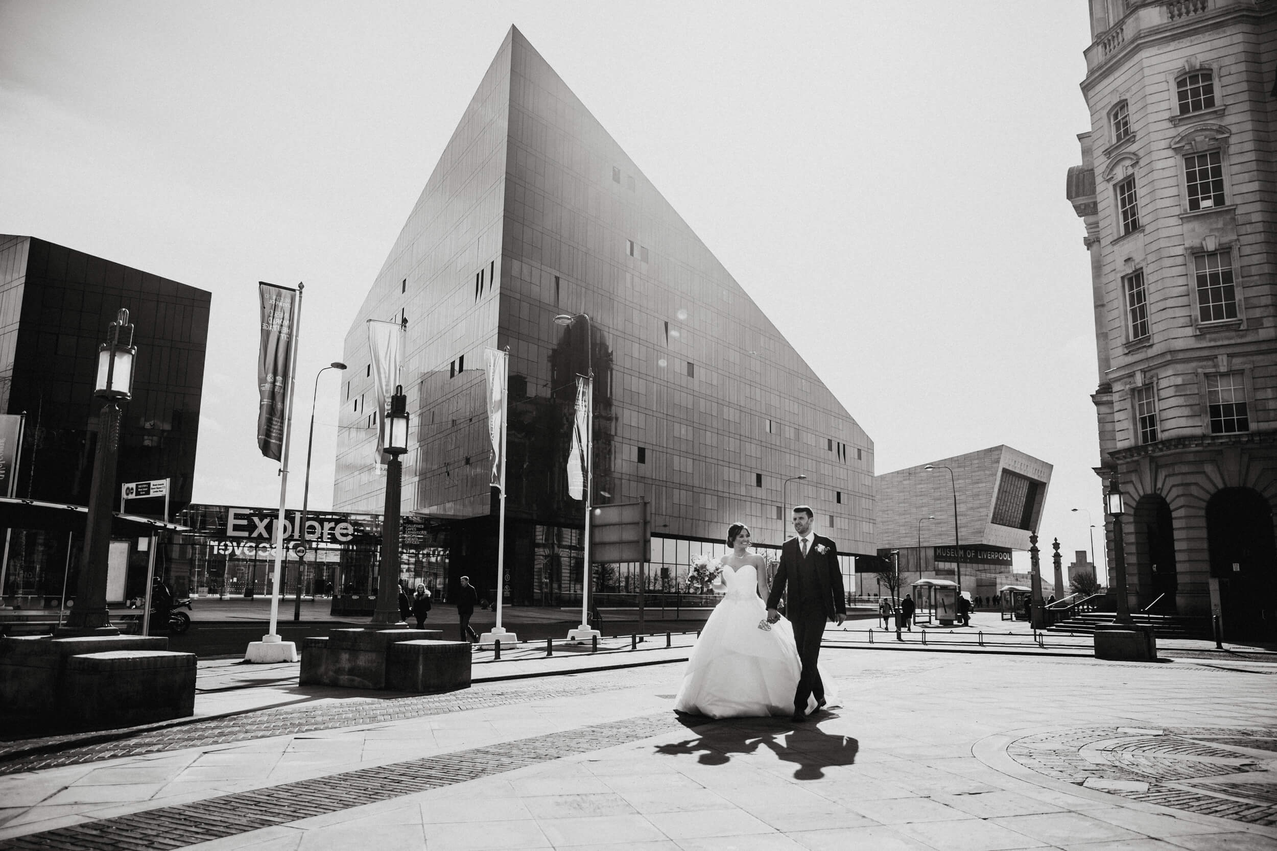 black and white photograph of bride and groom walking by Liverpool Docks outside 30 James Street