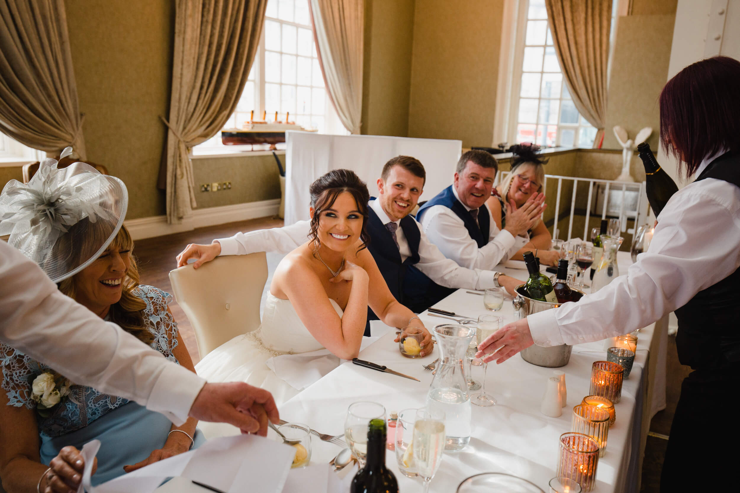 bride laughing at fathers speech on top table during wedding breakfast