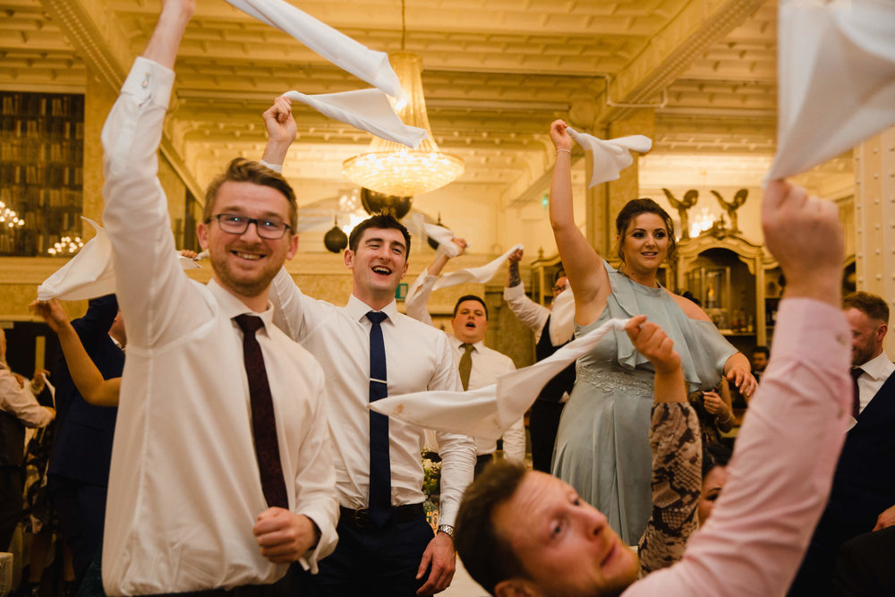 wedding guests waving napkins in the air in celebration