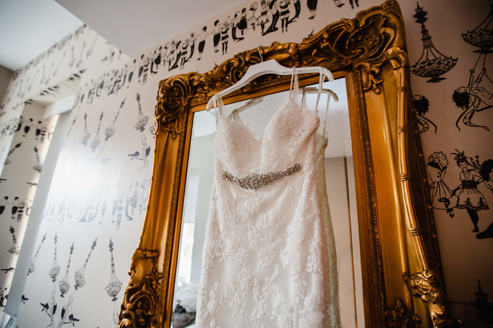 close up detail photograph of wedding dress hung on mirror