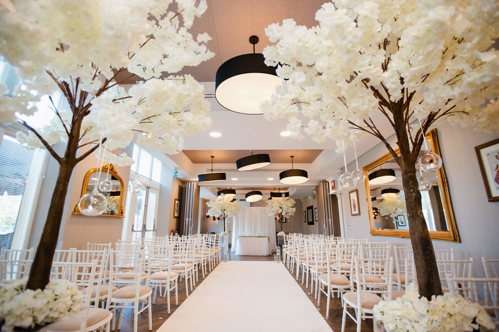 wide angle lens photograph of wedding ceremony room dressed with blossom trees and candles at oddfellows on the park