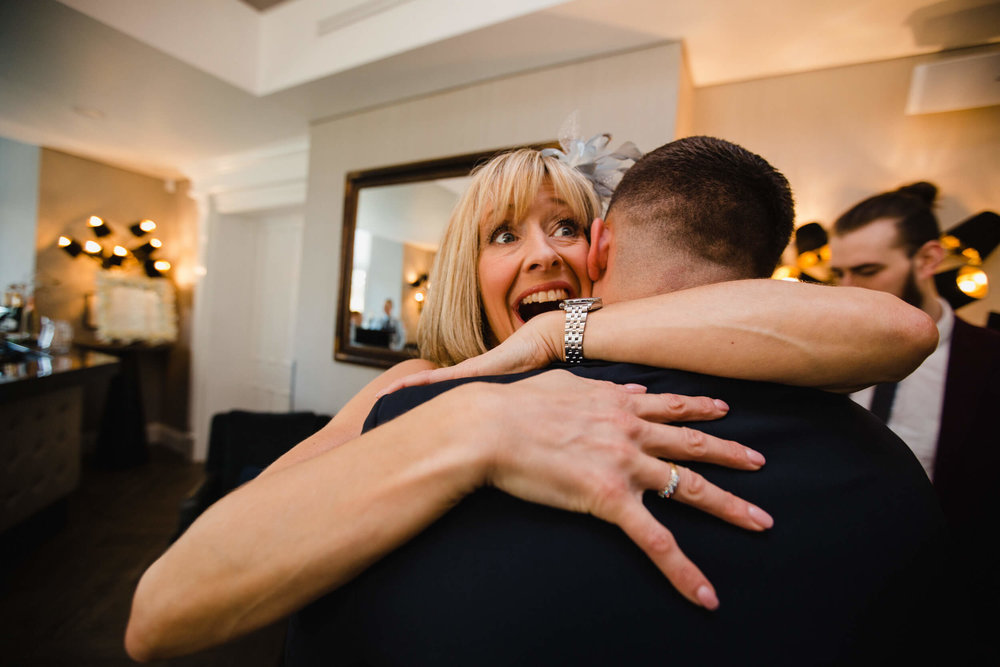 mother of groom sharing a hug with son before wedding processional commences