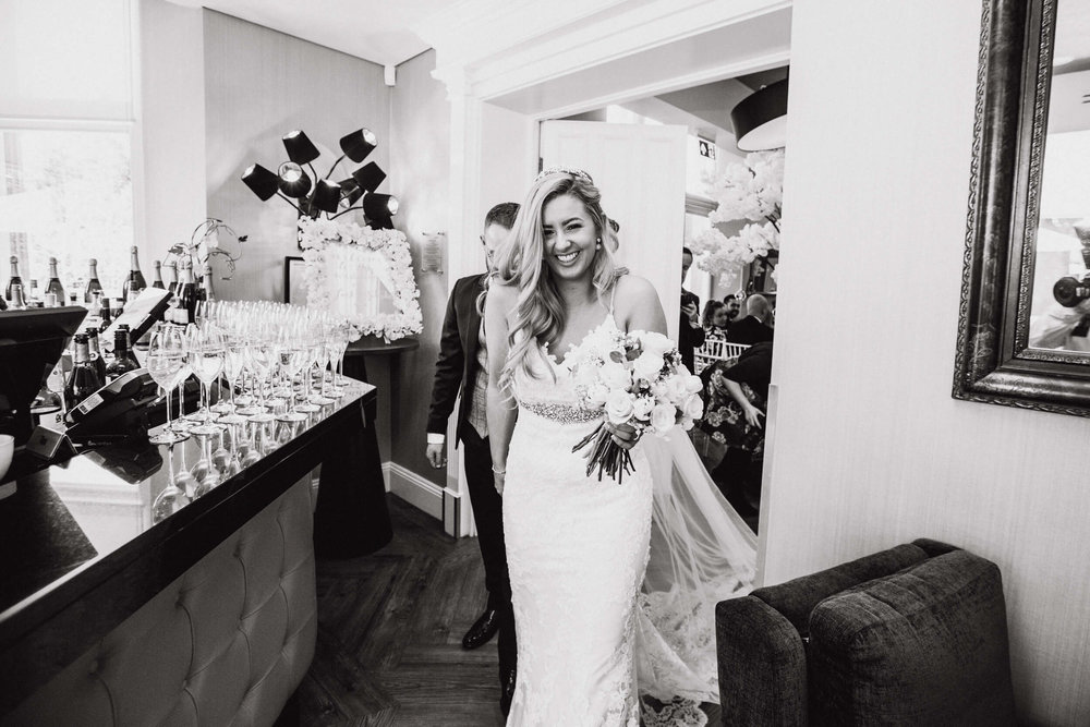 black and white photograph of bride smiling holding bouquet of flowers