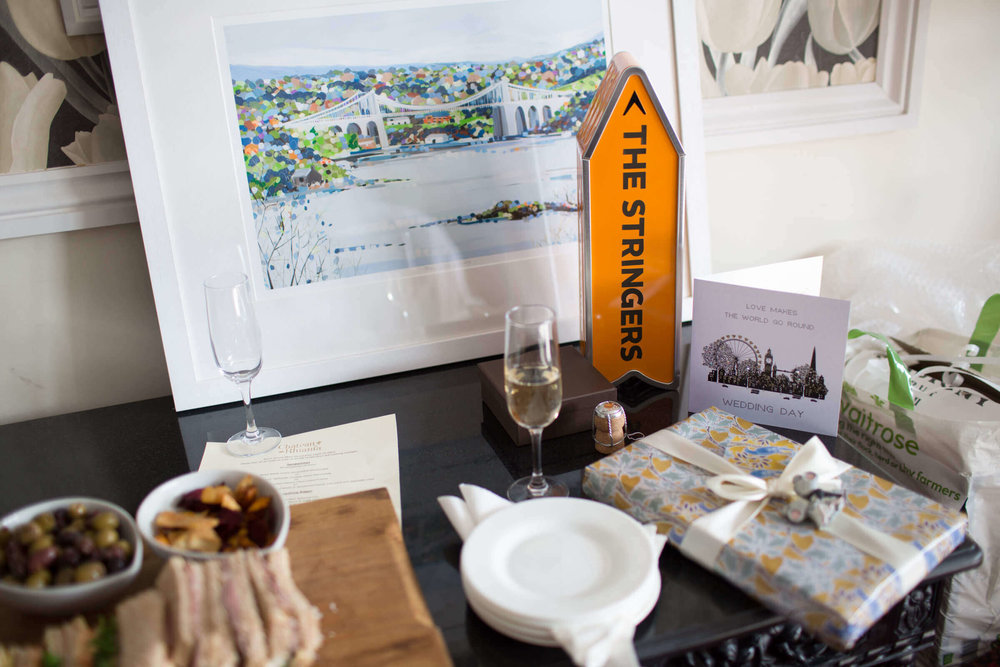 wedding gifts on table including a watercolour painting of chateau rhianfa on menai strait