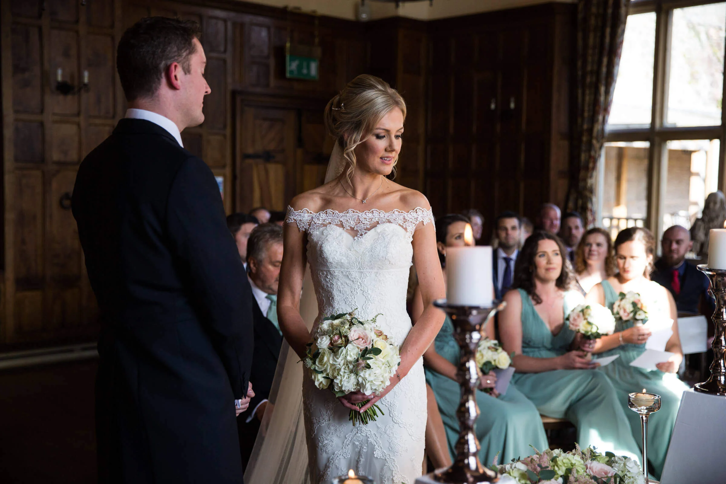 bride holding bouquet looking down at altar during ceremony