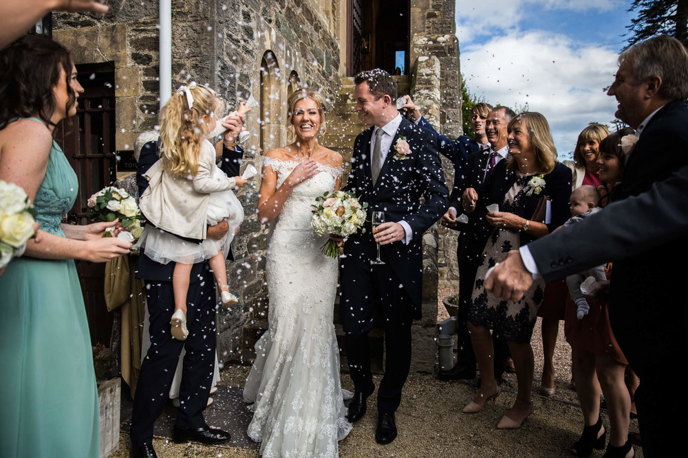 bride and groom congratulated with confetti on steps of chateau rhianfa