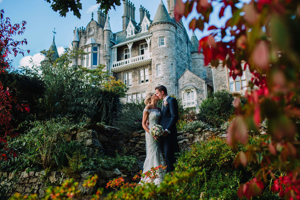 Bride and Groom sharing kiss in front of Chateau Rhianfa backdrop