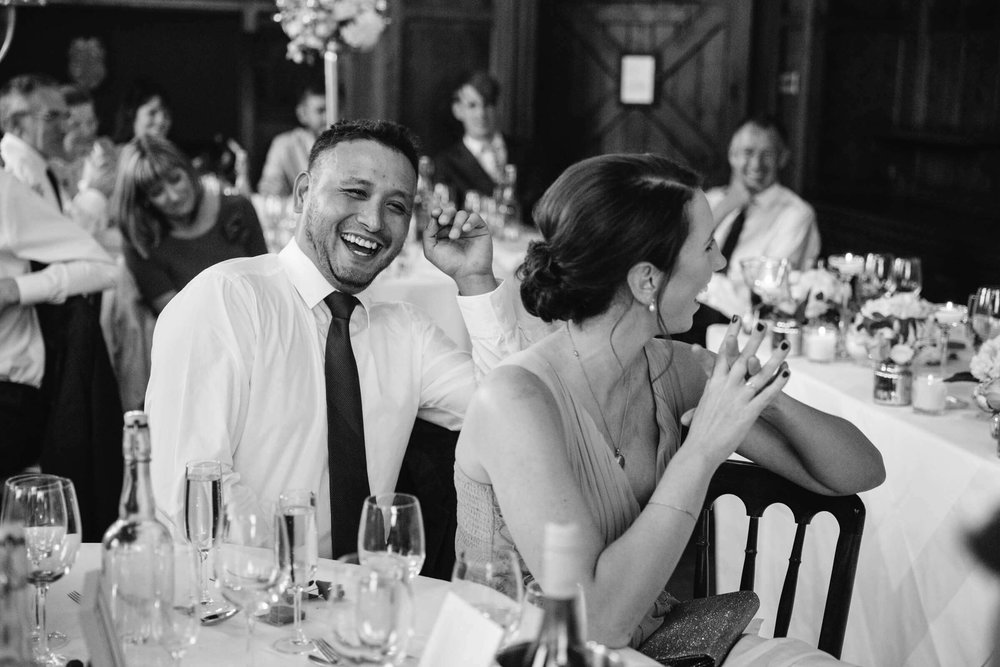 black and white photograph of wedding guest and bridesmaid laughing at speech