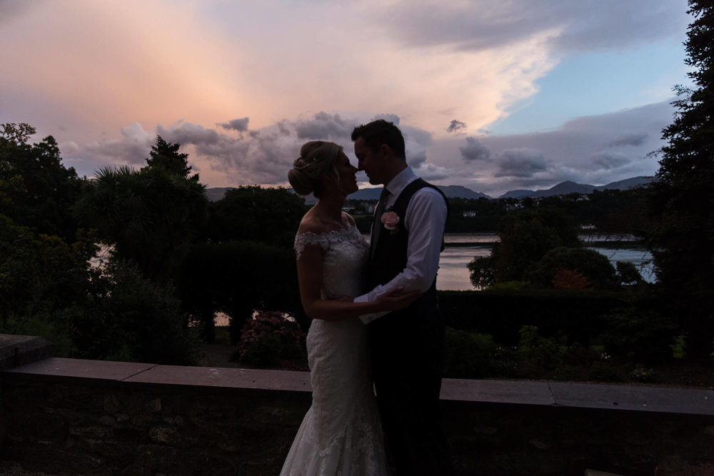 low light exposure silhouette portrait of bride and groom on terrace with sunset background