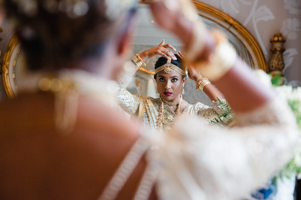 bride putting on tiara headdress in mirror of bridal suite at delamere manor wedding venue