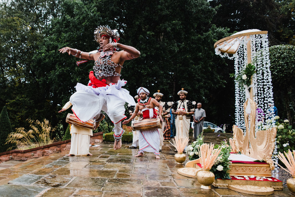 Sri Lanka wedding ceremony processional as dancer jumps into air with groom and ushers following