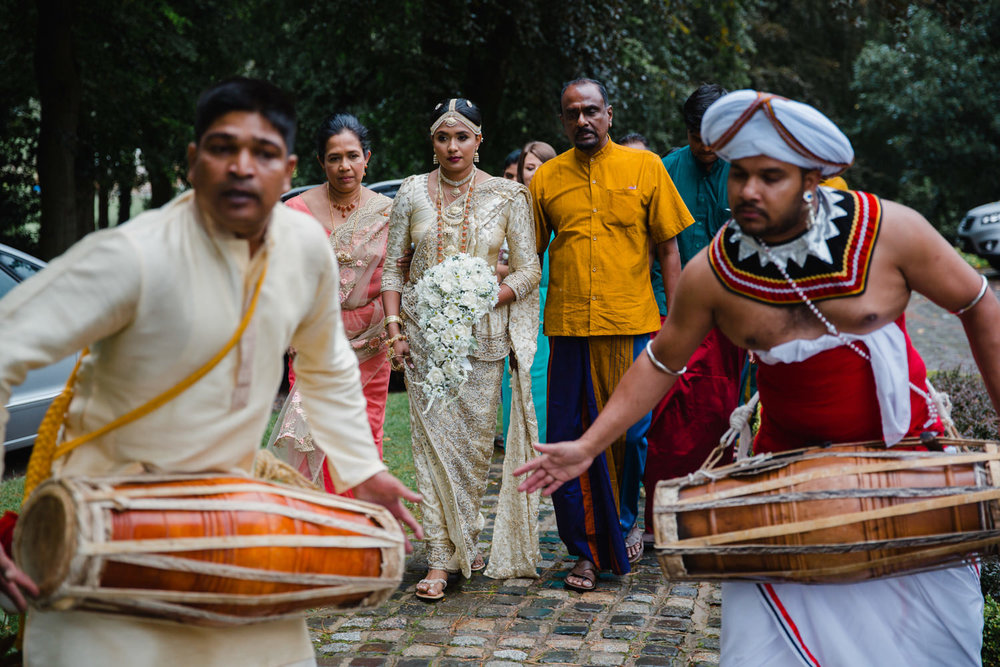 bride holding bouquet surrounded by family with drummers playing in foreground