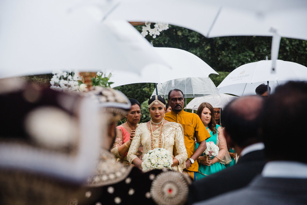 intimate photograph of bride sharing moment with groom under umbrellas at beginning of wedding ceremony