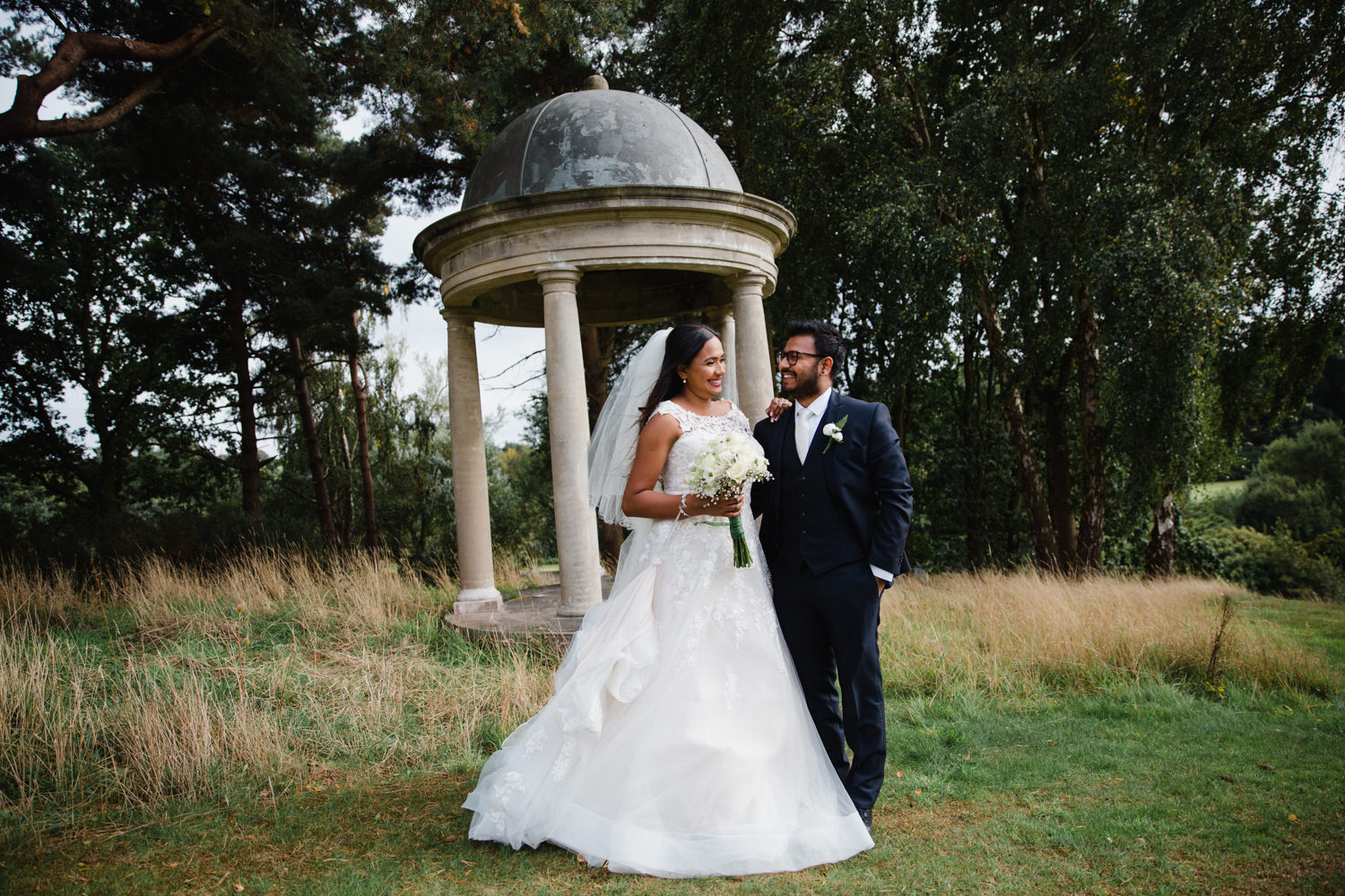 newly wedded couple pose for quick portrait in front of camera as bride smiles