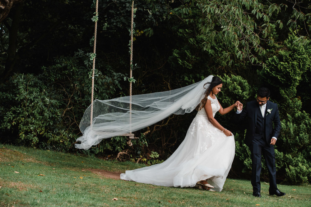 groom holds brides hand as veil blows in wind