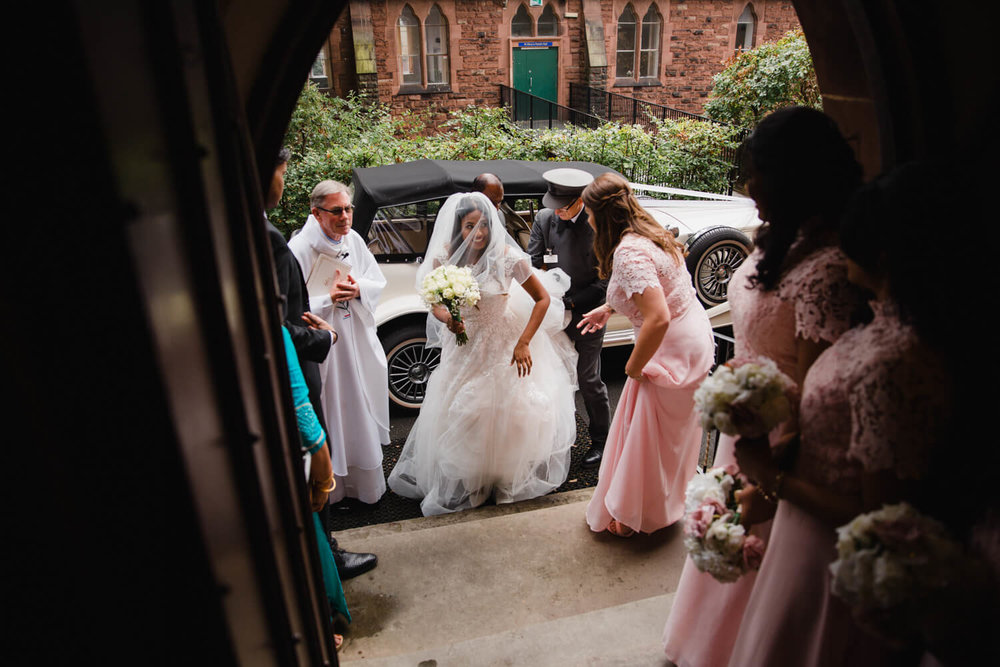 bride coming out of wedding car after arriving at church