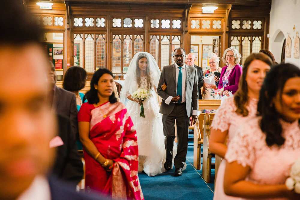 bride walking down aisle during processional in church