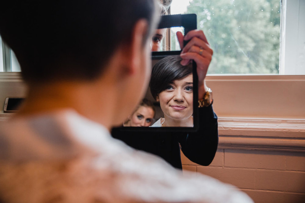 Copy of bride looking into mirror to see bridal make up applied