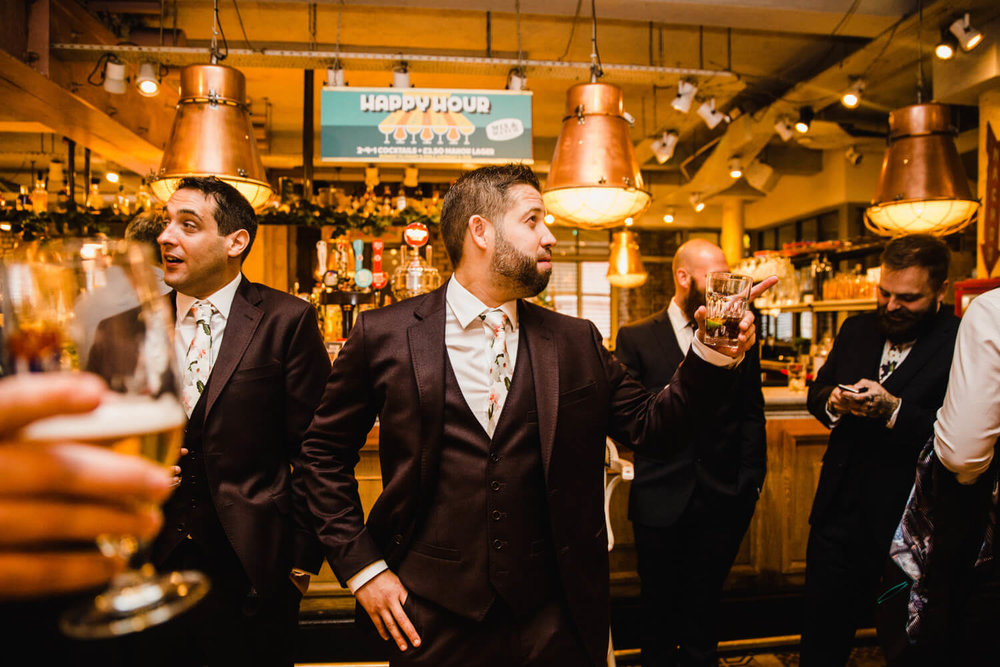 Copy of groom at the bar with groomsmen posing for photograph