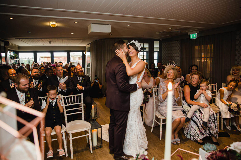 Copy of newlyweds share first kiss while being congratulated by wedding party at great john street hotel