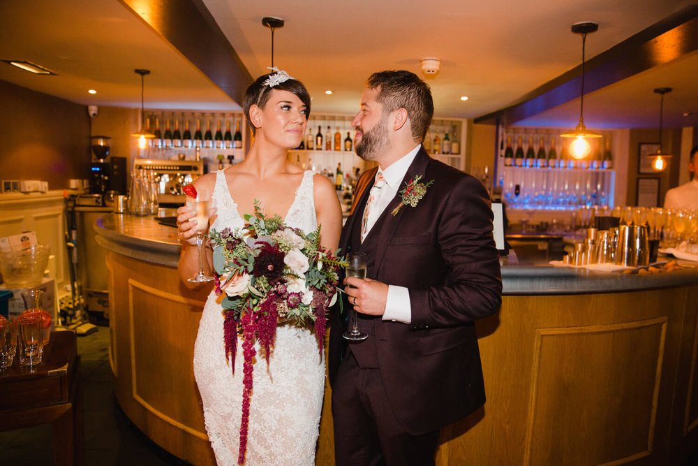 Copy of bride and groom share intimate moment together at bar after wedding ceremony