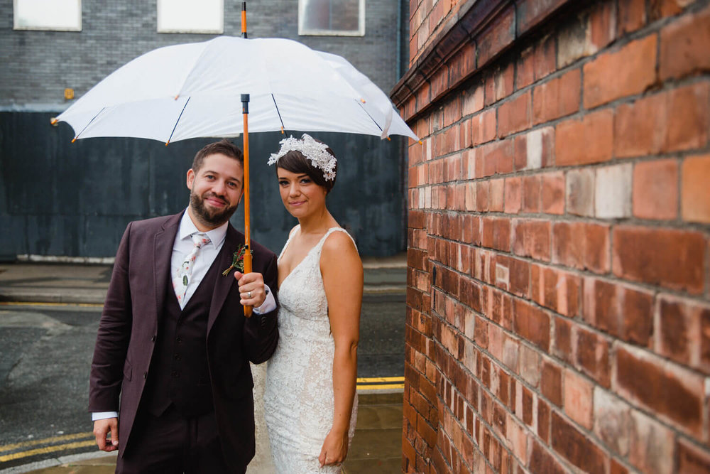 Copy of newlyweds stand on thoroughfare corner pavement for posed portrait