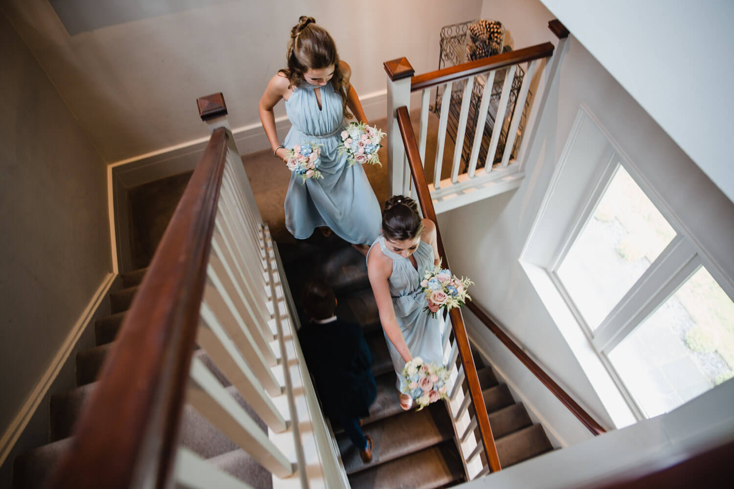 bridesmaids holding bouquets descending staircase at didsbury house hotel
