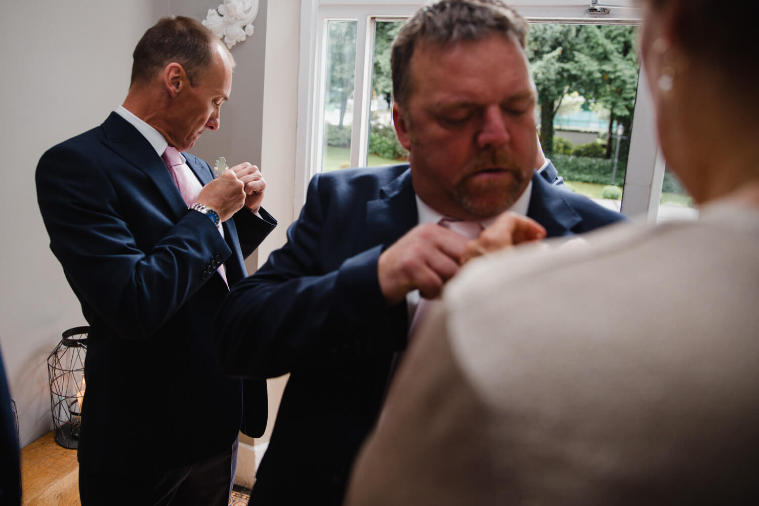 groomsmen attaching pinhole flowers to suits in lobby