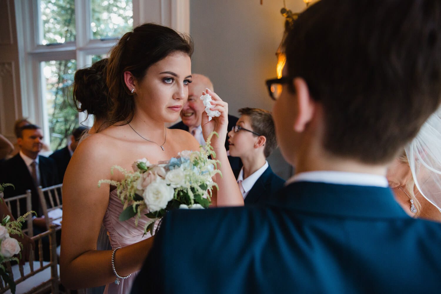 bridesmaid wipes away tear with tissue
