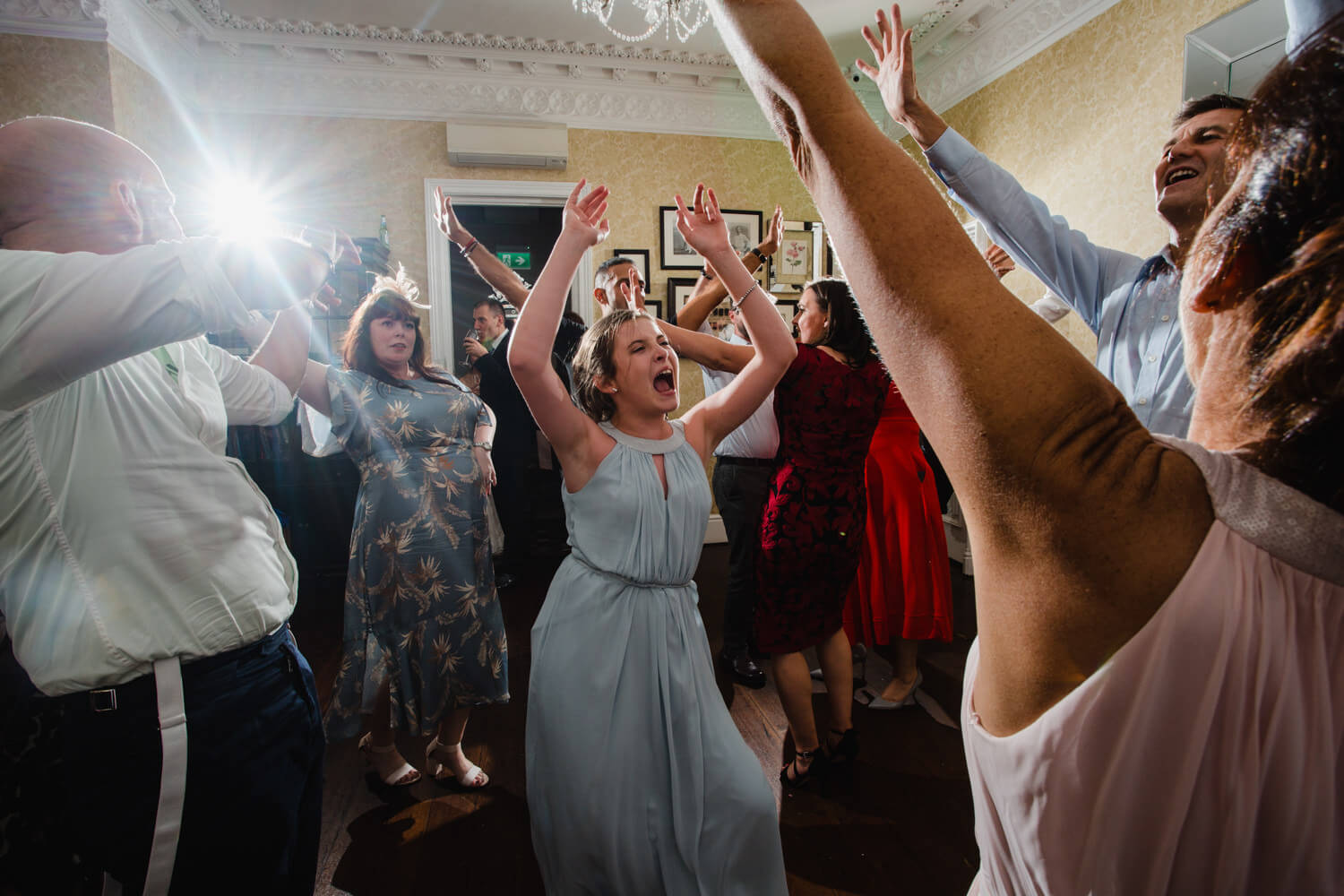 bridesmaids all dancing with hands in air as flash lights them up at correct exposure