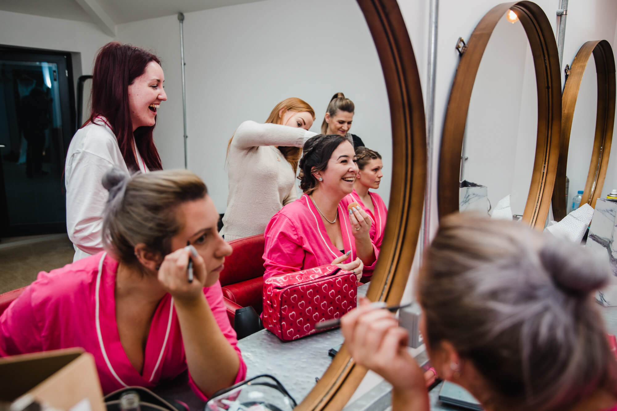 bridesmaids apply make-up in mirrors of bridal suite at owen house wedding barn