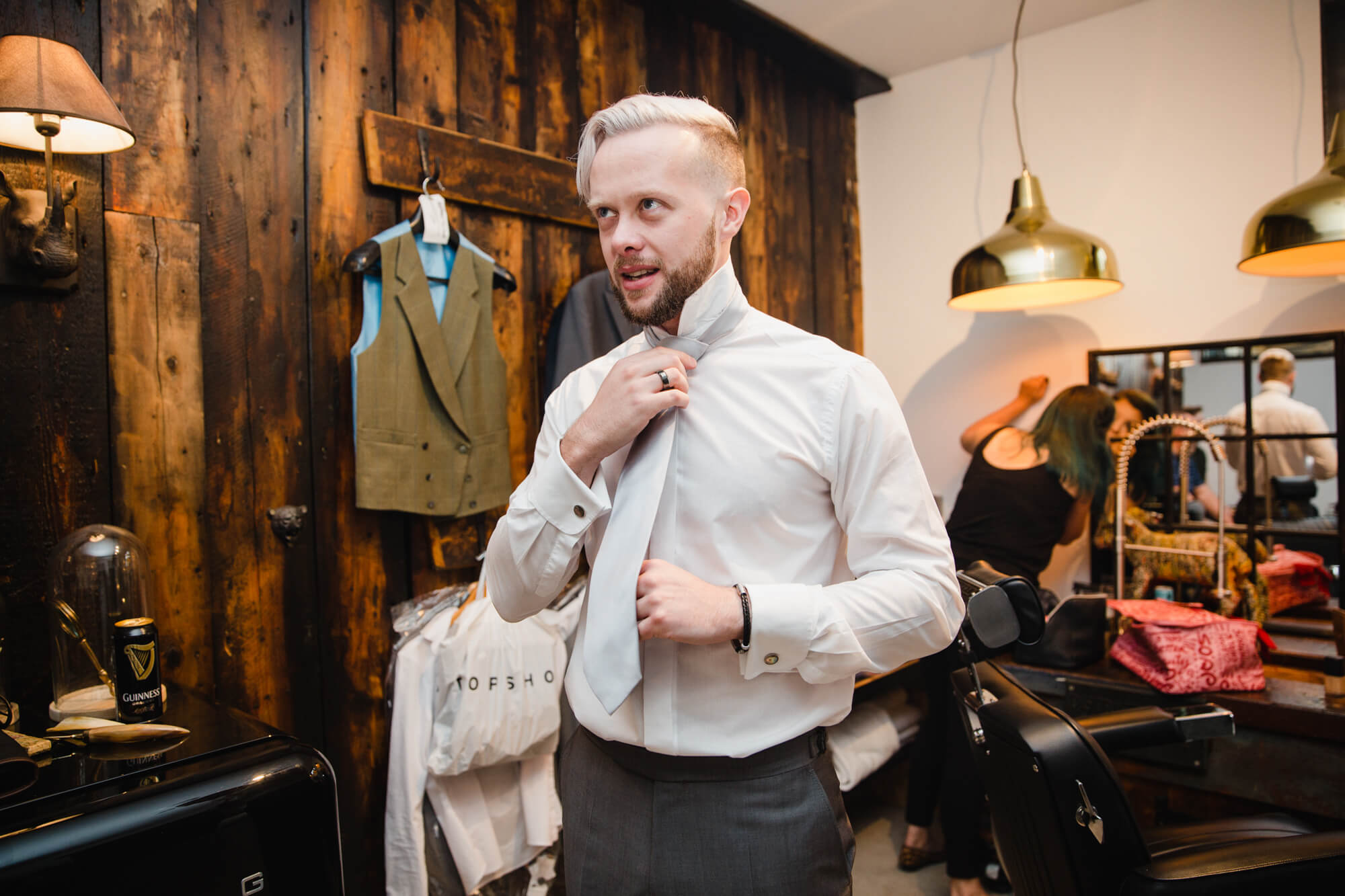 groom fastening tie before button hole flowers fitted