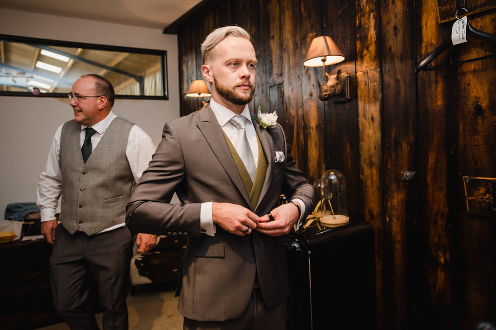 preparation digs is stylishly dressed as groom fastens suit jacket