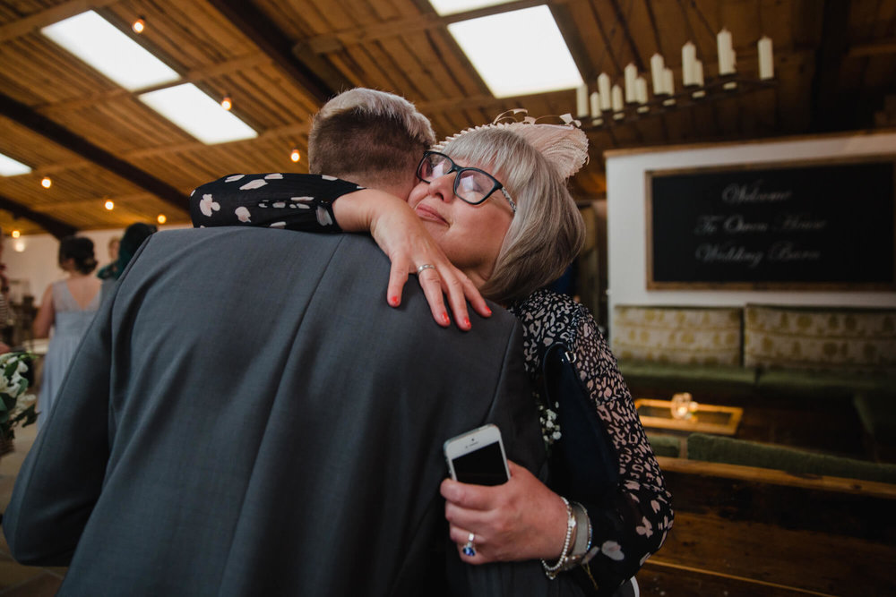 mother of groom shares intimate hug in candid photograph