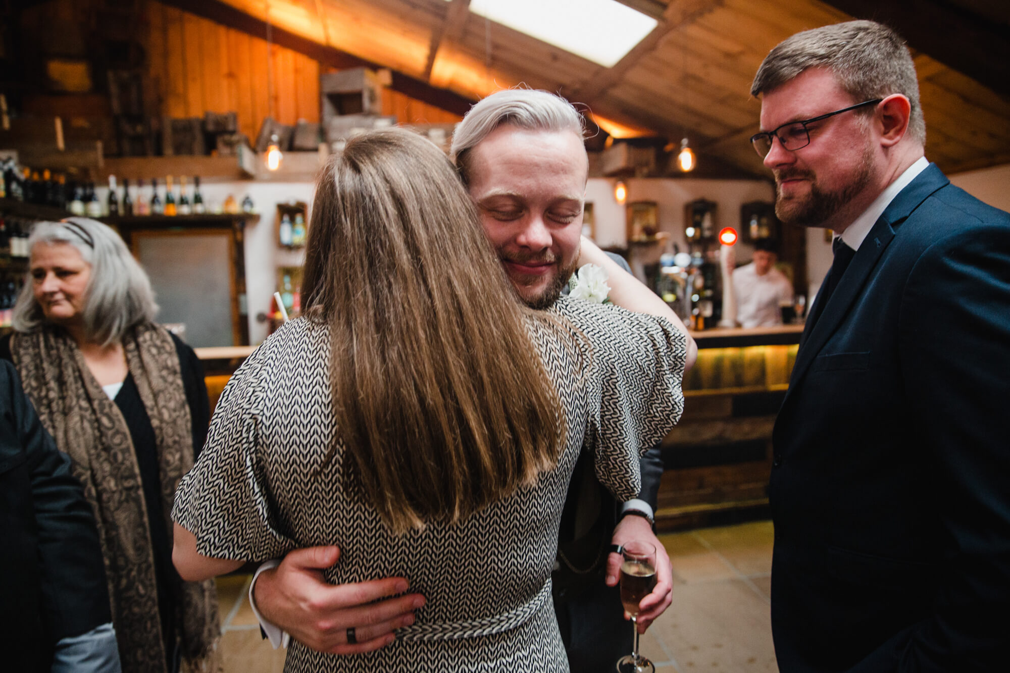 friend of newly married groom shares hug after wedding service