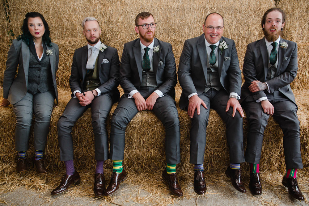 groomsmen sitting on hay bales in candid photography portrait 