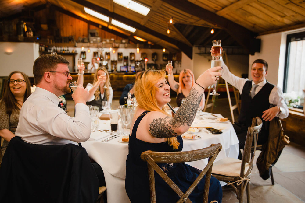 wedding guests raising glasses for toast to groom